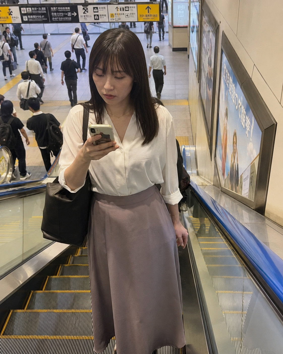 駅のエスカレーターでスマホを見る朝